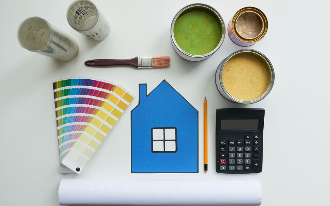 Several cans of paint, a brush, paint swatches and a calculator to represent how much does it cost to paint a house.